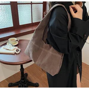 Detail of dark brown suede shoulder bag with cross stitching in a cozy cafe setting
