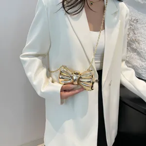 Detalle de un bolso de noche dorado con forma de lazo en acrílico y acabado de espejo lujo
