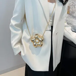 Detalle de un mini bolso de flor dorada con perla central y cadena fina en modelo