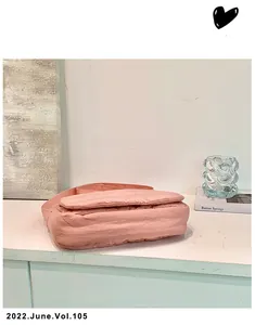 Detail of soft pink quilted crossbody bag with padded texture and matching strap
