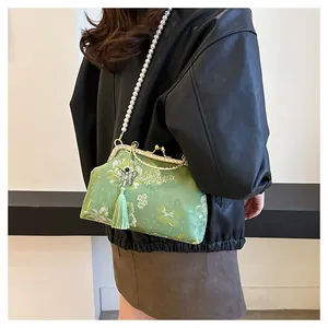 Détail de broderie florale et pompon sur sac coquille vintage avec bandoulière perle