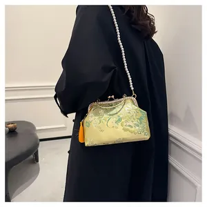 Détail de broderie florale sur sac jaune avec bandoulière perle et pompon orange