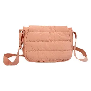 Minimalist coral pink quilted crossbody bag with adjustable strap on white background