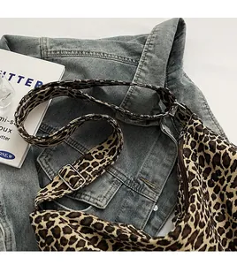 Detail of adjustable leopard print strap and metal buckle on canvas crossbody bag