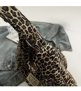 Detail of leopard print canvas bag with silver metal buckle and branded side label