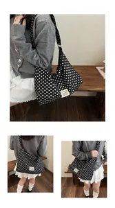 Detailed close-up of a high-capacity black and white polka dot canvas crossbody bag