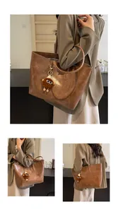 Détails du cabas marron vintage avec porte-clés monstre en peluche et coutures apparentes