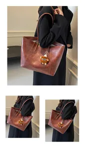 Détail d'un sac cabas vintage en cuir marron avec un joli porte-clés en peluche douce