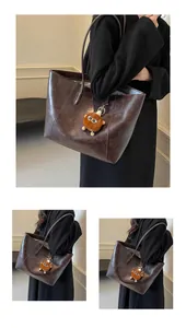 Gros plan du grand sac cabas marron foncé brillant avec pendentif en peluche