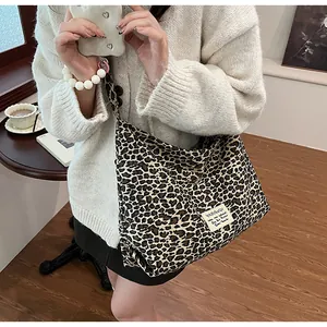 Detailed close-up of leopard print canvas tote bag featuring a stitched brand logo tag