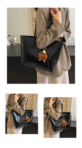 Détail d'un grand sac cabas noir avec un pendentif en peluche marron pour les trajets quotidiens