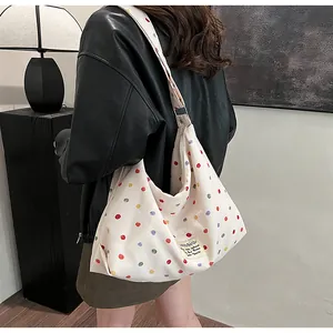 Detail of a white canvas tote bag with colorful polka dot print and fabric brand label