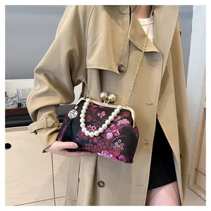 Detalle de bolso bordado con flores, asa de perlas, cadena y colgantes de borlas suaves