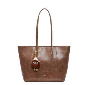 Détail du sac cabas en cuir marron texture vintage avec un charmant pendentif monstre