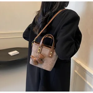Details einer Vintage-Eimertasche aus Canvas mit Lederbesatz und Hund-Anhänger-Accessoire
