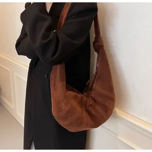 Macro detail of the brown suede hobo bag with distinctive pleated stitching and soft texture