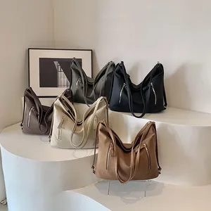Grands sacs cabas rétro en cinq couleurs mates sur un socle d'exposition épuré