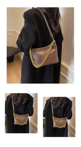 Detail einer braunen gesteppten Beuteltasche mit Goldkette und schmalem Schultergurt