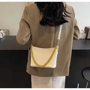 Detail einer beigen Stepptasche mit goldener Kette und verstellbarem Schultergurt