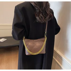 Braune gesteppte Umhängetasche mit goldener Kette auf der Schulter des Models