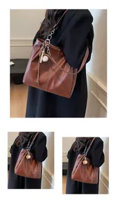 Detalle de bolso tote de cuero marrón con costuras blancas y correa de cadena
