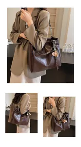 Detalle del bolso tote marrón oscuro con costuras blancas y correa de cadena plateada