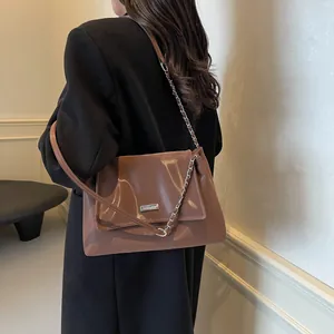Brown glossy faux leather underarm bag with metal chain strap and flap closure