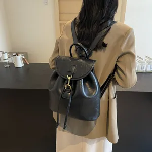 Detail of black PU leather backpack with vintage gold metal hook and drawstring closure
