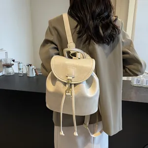 Close-up of a cream PU leather mini backpack with gold hardware and drawstring design