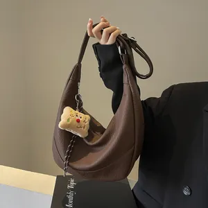 Detail of a brown lychee pattern hobo bag with a plush bear charm for daily commute