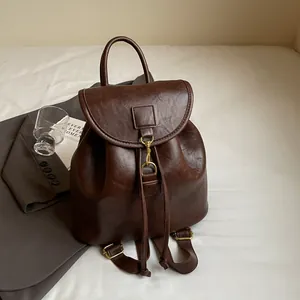 Detailed view of the dark brown PU leather backpack with vintage gold hook and drawstring