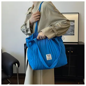 Detail of royal blue tote bag with unique vertical pleated texture and white woven label
