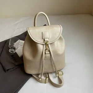 Detail of off-white faux leather backpack with drawstring closure and vintage gold hardware
