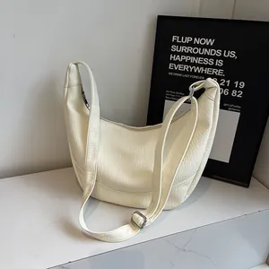 Close-up of white crescent shoulder bag with textured leather and silver buckle