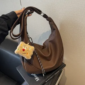 Deep brown crescent hobo bag with pebble leather texture and cute pendant accessory