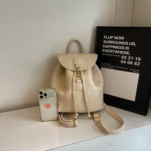 Close-up of cream PU leather backpack with vintage gold buckle on marble surface