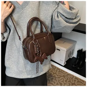 Detail der dunkelbraunen Boston Bag aus Leder mit Anhänger und feiner Textur