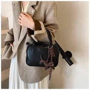 Detail der schwarzen Boston-Tasche aus Leder mit kreativem Anhänger am Tragegriff