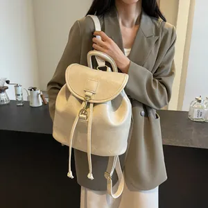Cream leather backpack with drawstring closure and gold buckles shown in lifestyle setting