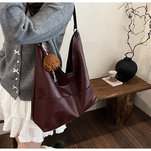 Burgundy oversized faux leather tote bag with plush dog charm and wide shoulder strap