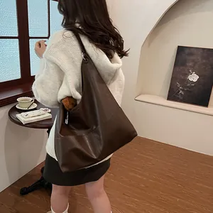 Brown leather tote bag with plush bear accessory in a cozy cafe setting for fall style