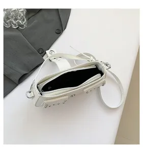 Κορυφαία άποψη της λευκής τσάντας με καρφιά, φερμουάρ και μαύρη εσωτερική επένδυση