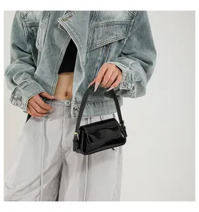 Dettaglio di una mini borsa baguette in vernice nera con fibbie in metallo dorato