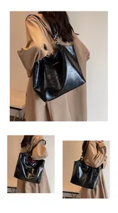 Detail of glossy pleated leather texture and gold metal accent on black tote bag