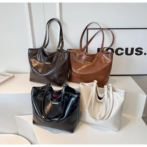 Detail shot of four glossy leather tote bags in dark brown, red, black, and cream colors