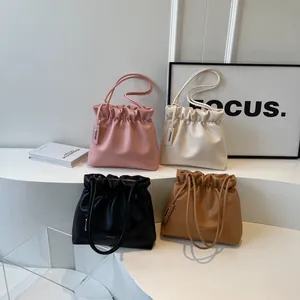 Chic pleated crossbody bucket bags in four colors arranged on minimalist white steps