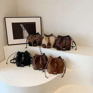 Collection de sacs seaux à cordon avec motif léopard sur des marches blanches minimalistes