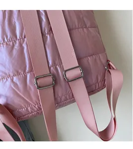 Detail of adjustable pink padded shoulder strap with silver buckle on a quilted backpack