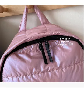 Detail of pink quilted puffer backpack featuring smooth black double zipper closure
