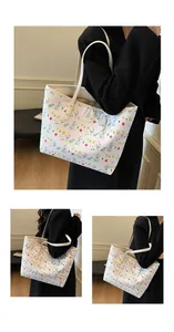 Dettaglio borsa shopper bianca con motivi floreali colorati e logo in metallo